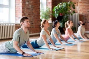 Fünf Personen praktizieren gemeinsam Yoga auf Matten – sie liegen mit dem Unterkörper auf dem Boden, während sie den Oberkörper anheben und den Blick nach oben richten, ganz im Zeichen von Kraft, Konzentration und Achtsamkeit.